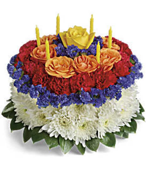 faux cake  white daisy on round,  purple statice outer ring followed by ring of red min carnations by orange spray roses,purple statice, 1 yellow rose in center, & 5 candles