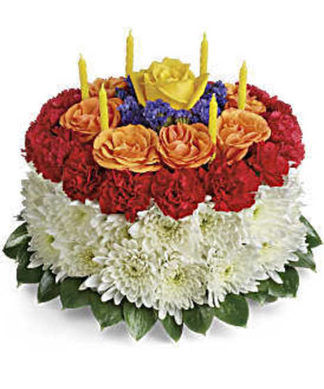 faux cake  white daisy on round,  purple statice outer ring followed by ring of red min carnations by orange spray roses,purple statice, 1 yellow rose in center, & 5 candles