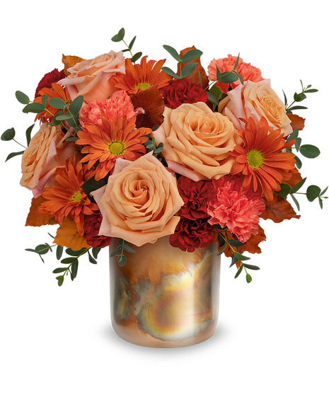 copper hue cylinder with  light orange roses, orange carnations, miniature maroon carnations, bronze daisy and brown copper beech arranged with parvifolia eucalyptus.
