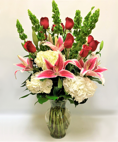 red roses, stargazers, white hydrangeas, bells of Ireland, salal in clear glass vase
