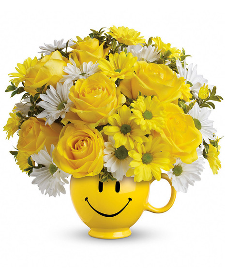 Yellow roses, spray roses and daisy spray chrysanthemums along with white daisy spray chrysanthemums and oregonia are delivered in the one and only Be Happy® mug. 