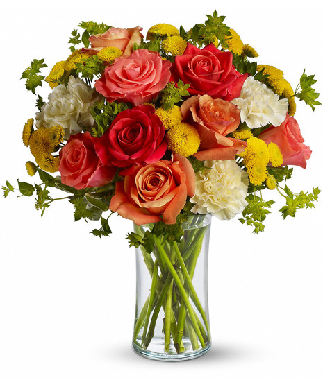 Dark orange, coral and orange roses, light yellow carnations, yellow button spray chrysanthemums and greens fill a slender gathering vase. It's a kiss of summer! 