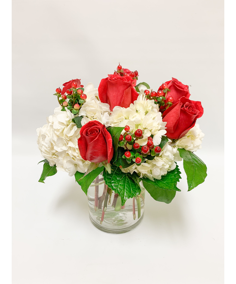 red roses white hydrangeas red hypericum berries nestles in salal come arranged low and compact in clear glass cylinder