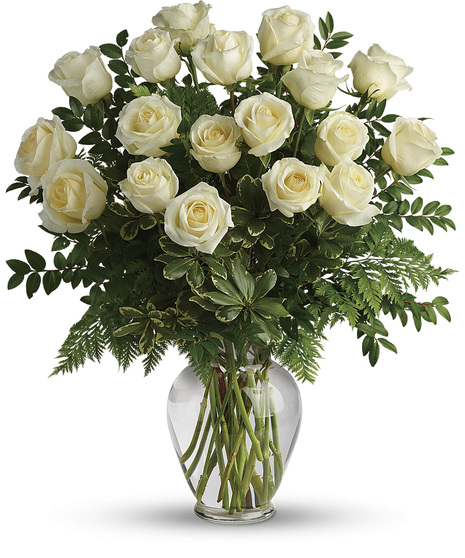 white roses in clear vase with leather leaf salal and ruscus