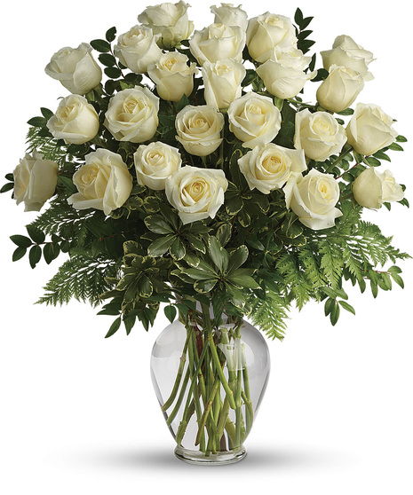 white roses in clear vase with leather leaf salal and ruscus