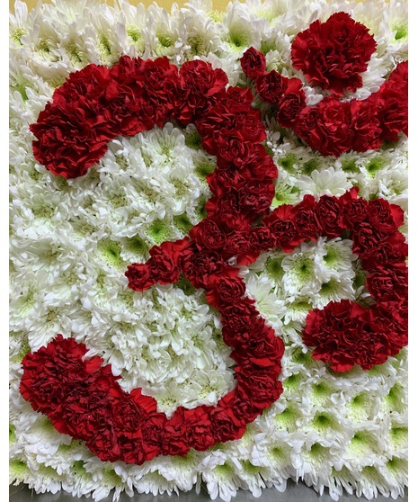 square shape foam on green easel with white mums in background and red carnations shaped to read ohm/aum