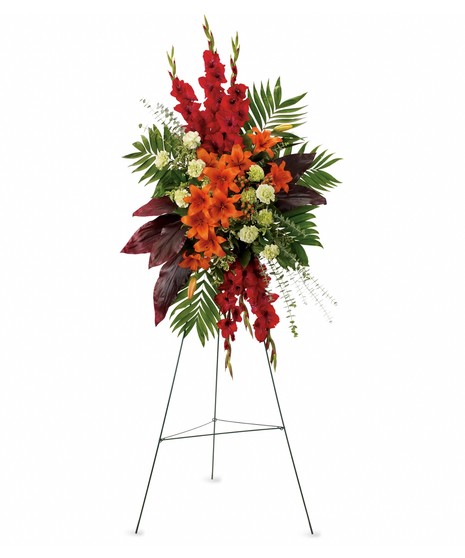 standing spray with orange lilies, red gladiola and ti leaves, green carnations and emeral and jade on green easel