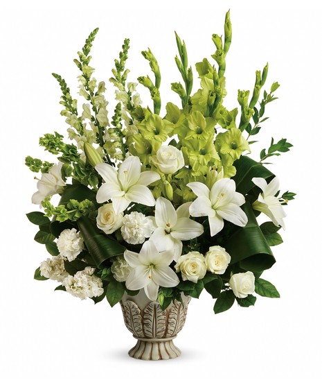 White roses, asiatic lilies, green gladioli, white carnations, bells of ireland, white snapdragons, and white stock are accented with myrtle, green ti leaves, and lemon leaf. 