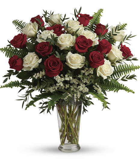red and white roses with salal, eucalyptus, and fern in clear glass vase with white filler flowers