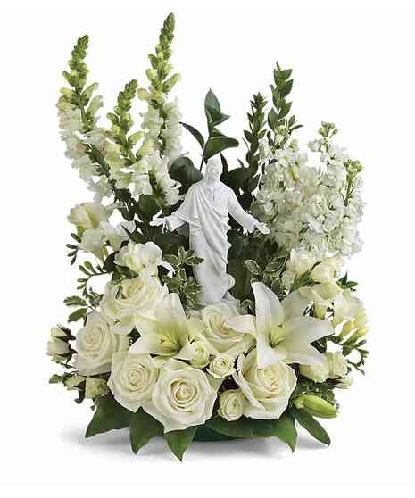 jesus statue in center with white and craeam roses, spray roses, stock, snap dragons, lilies and salal and ruscus in a three sided arrangement 
