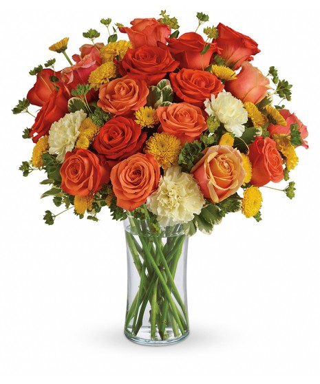 Dark orange, coral and orange roses, light yellow carnations, yellow button spray chrysanthemums and greens fill a slender gathering vase. It's a kiss of summer! 