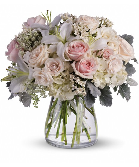 Gorgeous flowers such as white, crème and light pink roses, white oriental lilies and delicate Queen Anne's lace with a touch of silvery dusty miller, all in a classic vase.