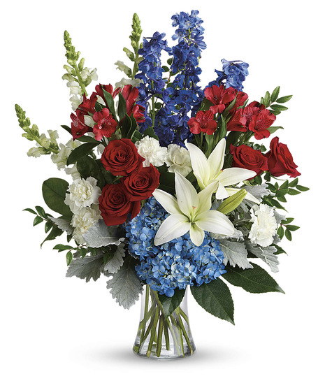 blue hydrangea, red roses, white lilies, red alstroemeria, white carnations, blue delphinium, white snapdragons, huckleberry, dusty miller, aralia, salal in a gathering vase