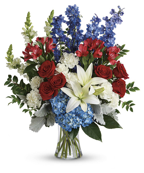 blue hydrangea, red roses, white lilies, red alstroemeria, white carnations, blue delphinium, white snapdragons, huckleberry, dusty miller, aralia, salal in a gathering vase
