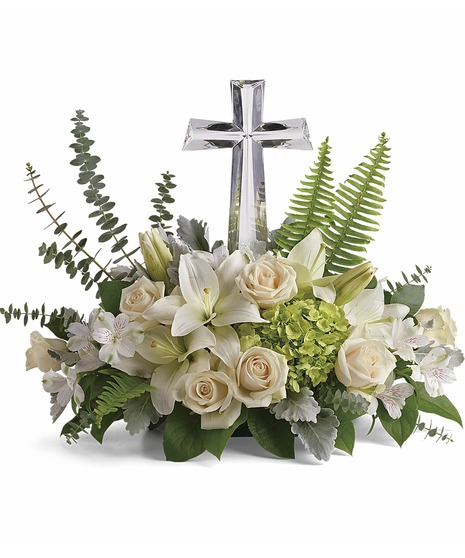 crystal cross at center with white roses, spray roses, lilies, alstromeria nestled in eucalyptus, salal and leather leaf to make a sympathy piece to cherish