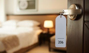 A hotel room door with a key card hanging from the handle labeled 
